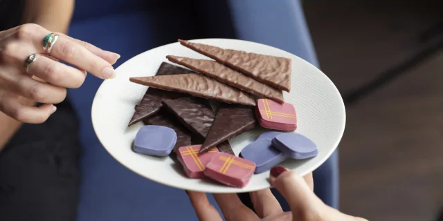 Assiette pleine de chocolats, une main la porte et une main se sert