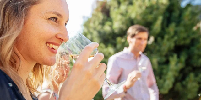 Femme portant un verre de vin blanc à son nez