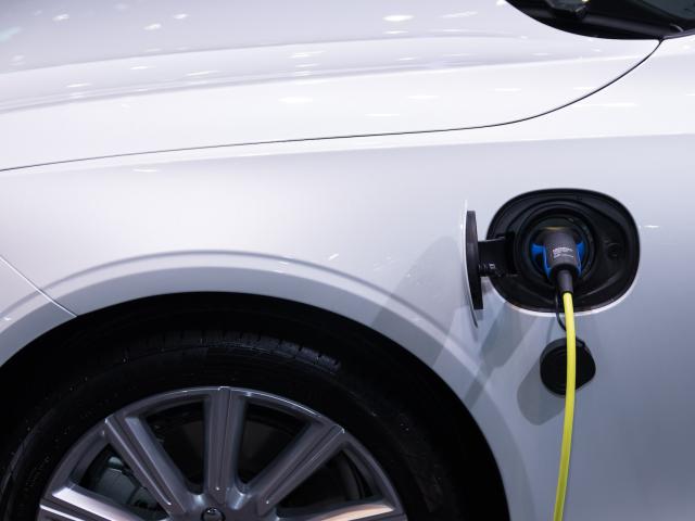 Plan rapproché sur la prise de recharge sur un véhicule électrique blanc en cours de charge