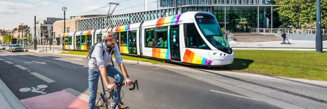 Homme à vélo avec le tram passant derrière, devant le Centre de Congrès d'Angers