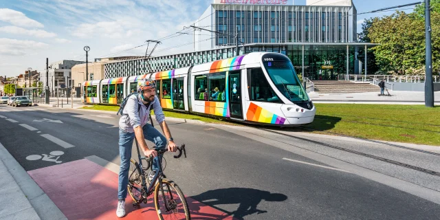 Homme à vélo avec le tram passant derrière, devant le Centre de Congrès d'Angers