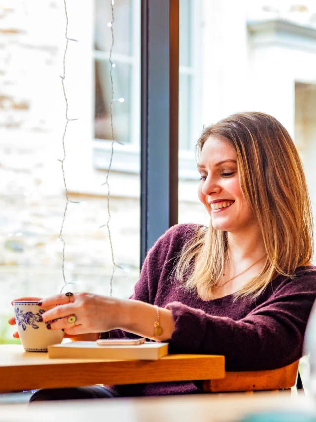 Femme attablée à une table dans un salon de thé angevin en train de déguster son chocolat chaud. ©Christophe Martin