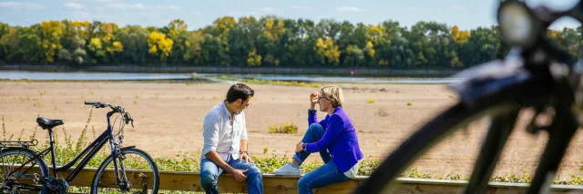 A couple sat on the Loire banks with their bike beside