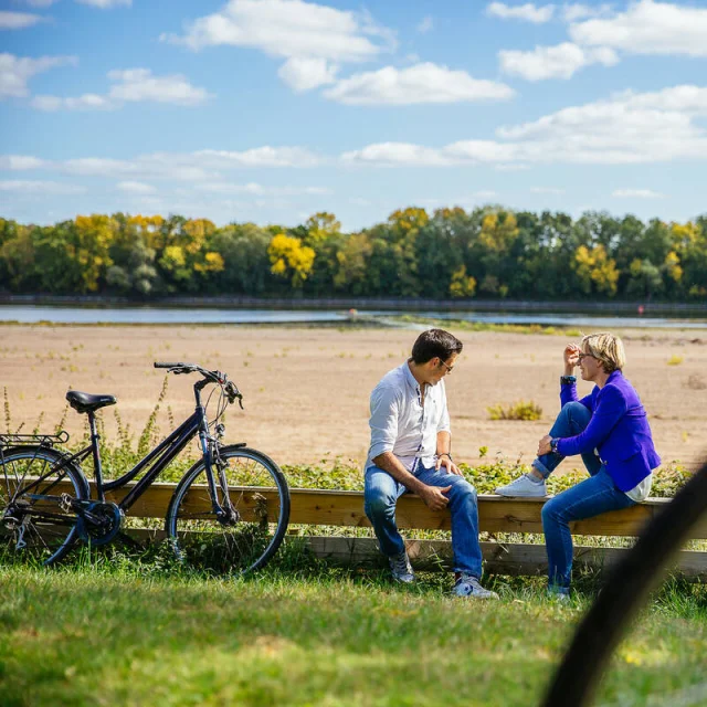 A couple sat on the Loire banks with their bike beside