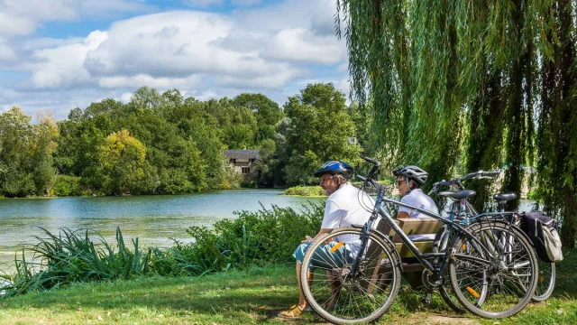 Cyclistes assis sur un banc au bord du Loir à Villevêque