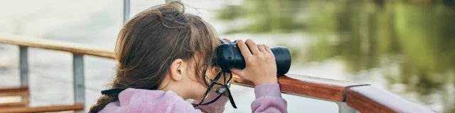 Child looking through binoculars on Loire Odysée