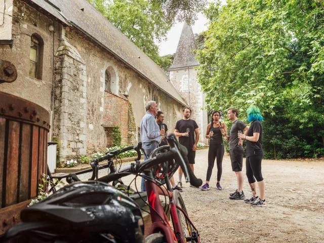 Cyclistes prenant un verre à l'extérieur du chai, leurs vélos au 1er plan.