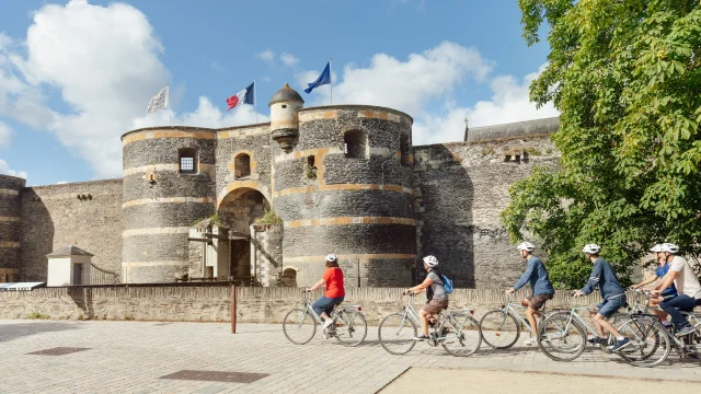 5 people cycle past Angers fortress