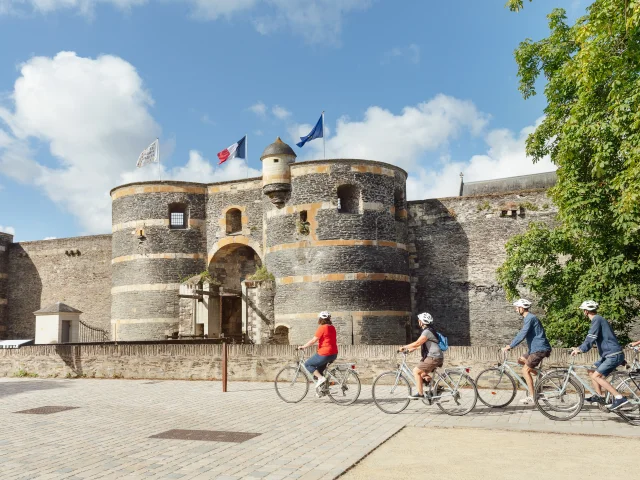 5 people cycle past Angers fortress