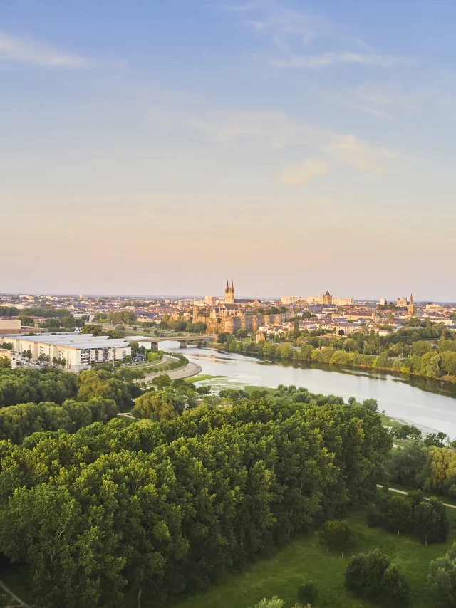 Vue aérienne sur un parc au premier plan, la Maine puis la ville d'Angers à l'arrière-plan, ciel rosé