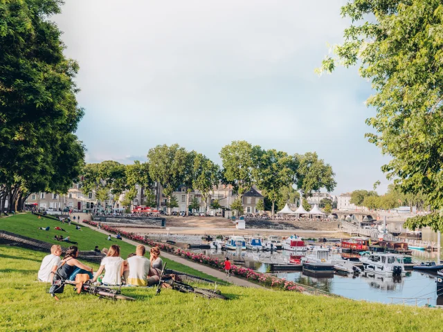 3 personnes assises sur l'herbe et regardant le port d'Angers