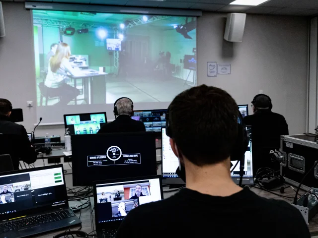 Several people behind computers during a conference screen broadcast