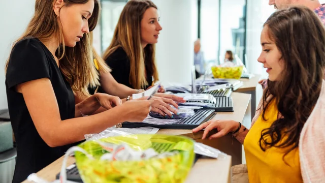 Plusieurs jeunes femmes accueillent les visiteurs et manipulent des badges