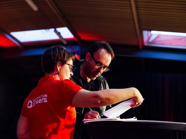 Une femme portant un polo rouge montre un document à un homme