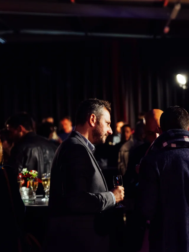 Plusieurs personnes rassemblées durant un cocktail, ambiance plutôt sombre