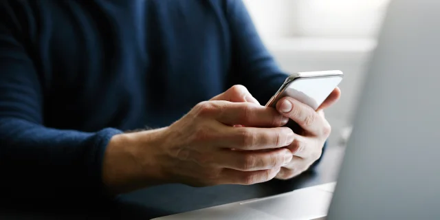 Man with mobile phone and laptop in office