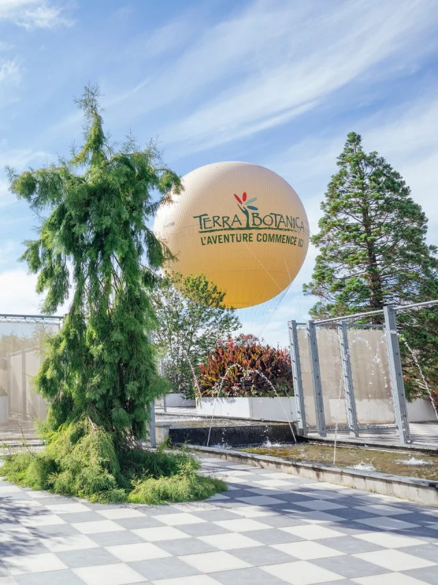 Plan large du parc avec une famille qui se promène et le gros ballon jaune en arrière-plan en l'air