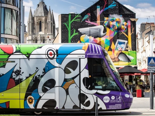 Streetcar dressed in Jean Moderne's Les Ecouteurs theme as part of Échappées d'Art 2019, in front of the Apocalypsis mural, placette Saint-Aubin and place du Ralliement