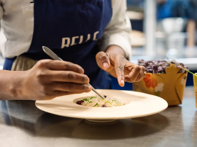 Plan rapproché d'un cuisinier qui dresse une assiette