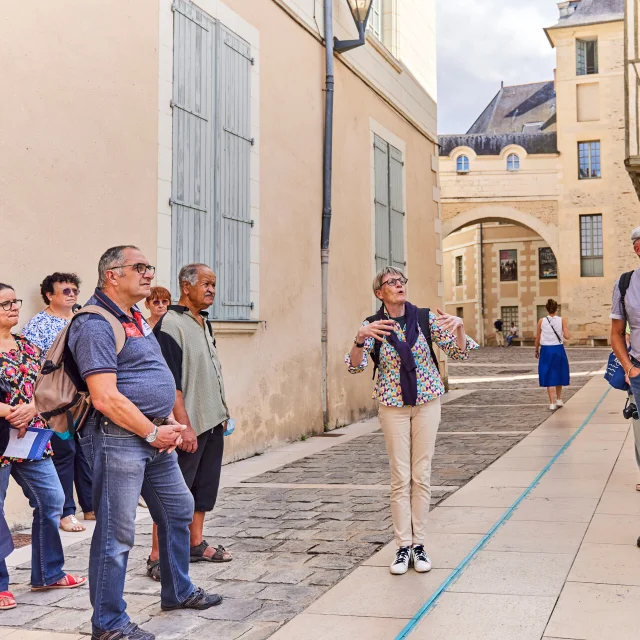 Groupe de seniors écoutant les explications de la guide conférencière dans une rue d'Angers