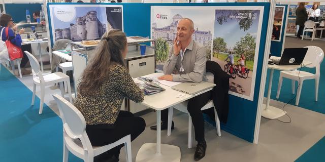 Plan large du stand de Destination Angers au salon Rendez-vous en France, 2 personnes discutant à une table