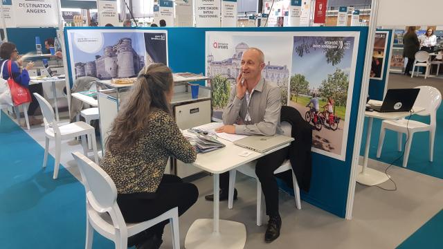 Plan large du stand de Destination Angers au salon Rendez-vous en France, 2 personnes discutant à une table