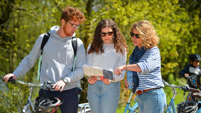 Trois personnes regardant une carte à côté de leur vélo