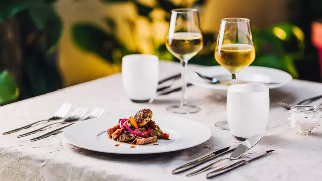 Table dressée avec deux verres de vin blanc et une assiette garnie