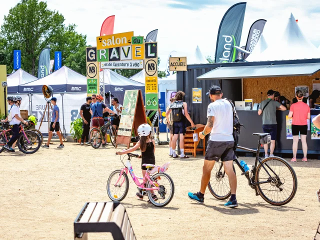 Un père et sa fille, à vélo, arrivent à l'entrée du village