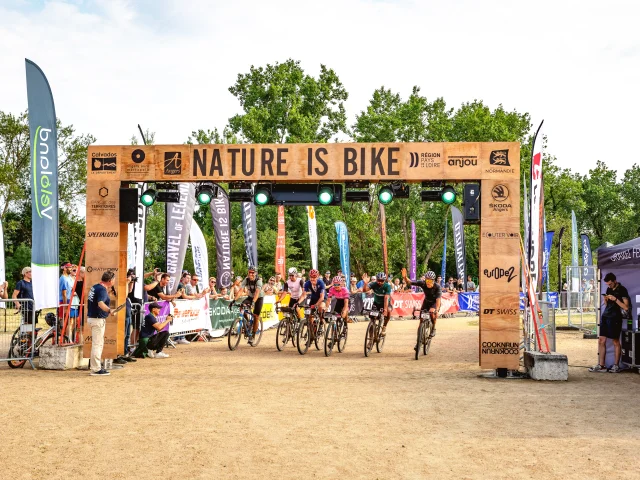 Passage sous l'arche d'arrivée de plusieurs coureurs cyclistes